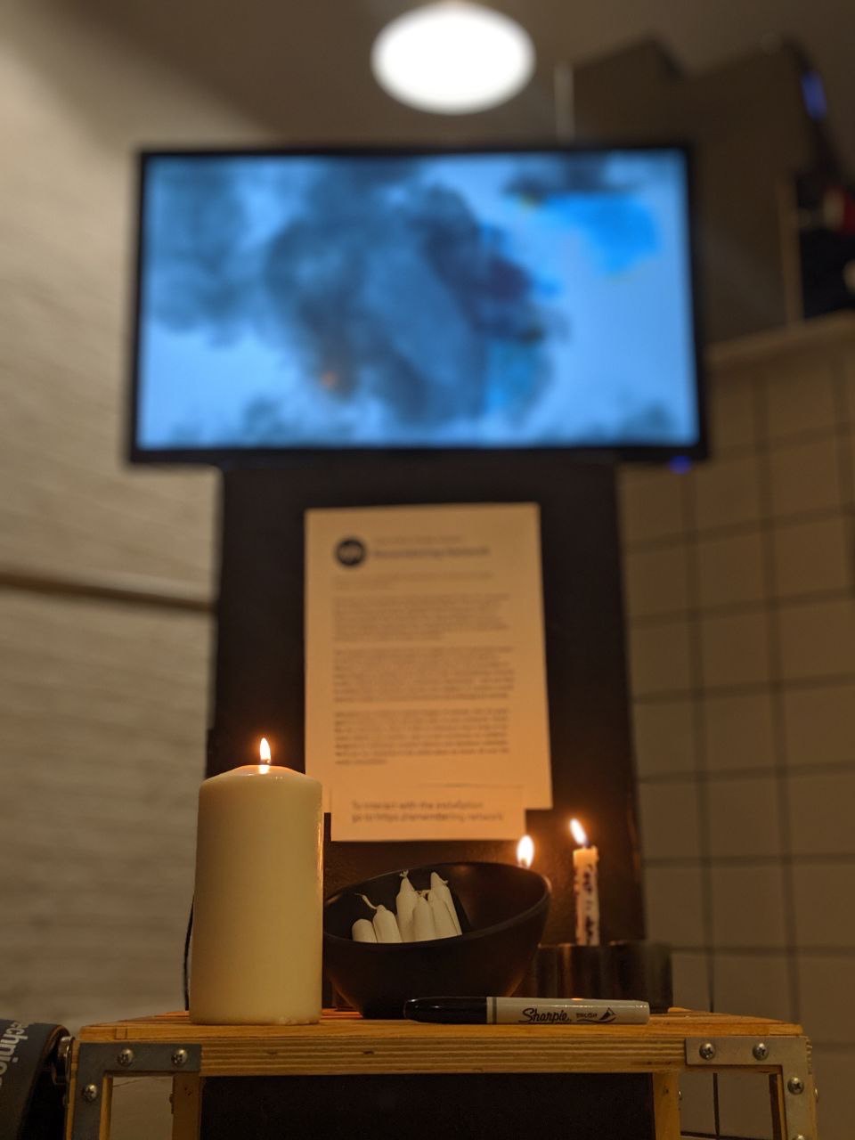 Remembering Network by artist Sarah Friend installed at Radical Networks with candle-lit shrine in front of digital display
